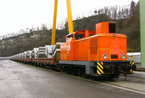 [OeBB-Diesellok Em 4/4 Nr. 22 mit 12 4-achsigen Wagen beladen mit Tübbingen im Anschlussgleis Marti zur Abfahrt bereit.]